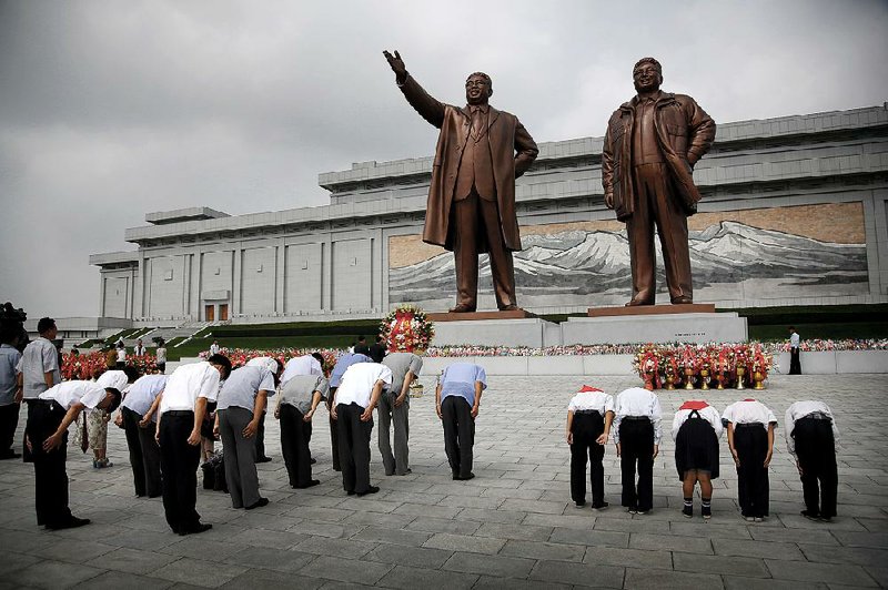 North Koreans bow before bronze statues of late leaders Kim Il Sung (left) and Kim Jong Il at Mansudae, a hill in Pyongyang, during events Monday marking the 62nd anniversary of the Korean War’s end. 