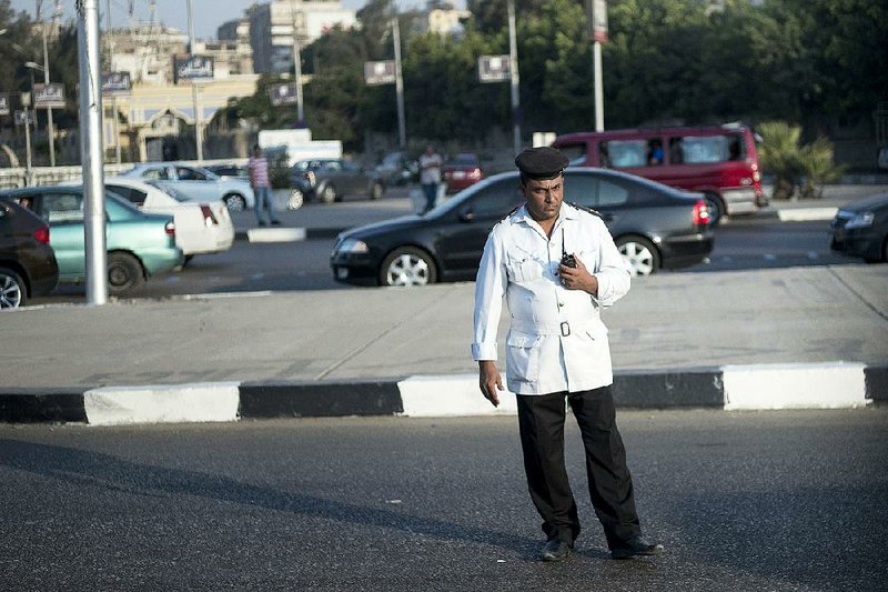 An Egyptian traffic officer watches as a motorcade with U.S. Secretary of State John Kerry passes Saturday in Cairo. 
