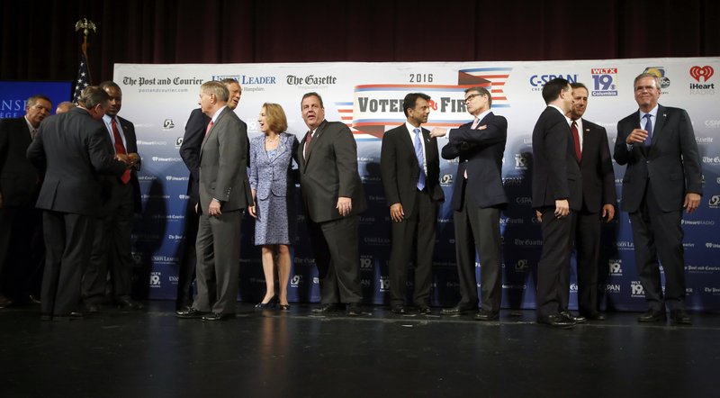 Republican presidential candidates John Kasich, left, Ben Carson, third from left, Lindsey Graham, George Pataki, Carly Fiorina, Chris Christie, Bobby Jindal, Rick Perry, Scott Walker, Rick Santorum and Jeb Bush speak among themselves after a forum Monday, Aug. 3, 2015, in Manchester, N.H. Second from left is Saint Anselm College president Steven DiSalvo.