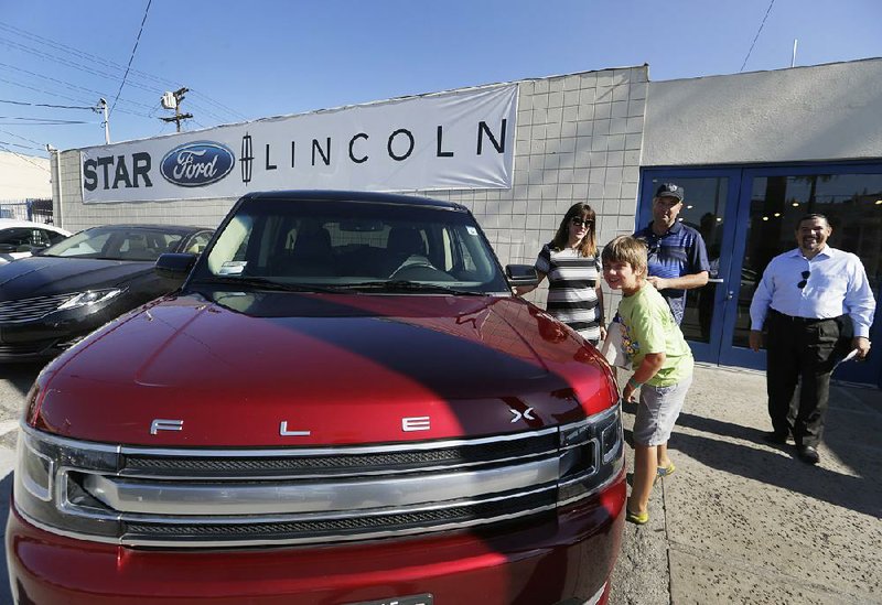 A family poses with a 2013 Ford Flex Limited at Star Ford Lincoln in Glendale, Calif., in early July. Summer discounts to clear out 2015 models helped attract buyers to auto lots in July.