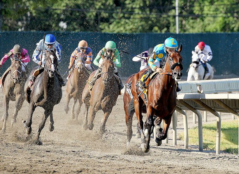 American Pharoah and jockey Victor Espinoza (right), in their first race together since winning the Belmont Stakes on June 6 to complete the Triple Crown, lead the field around the final turn en route to capturing the $1,750,000 Grade I Haskell Invitational on Sunday at Monmouth Park in Oceanport, N.H.