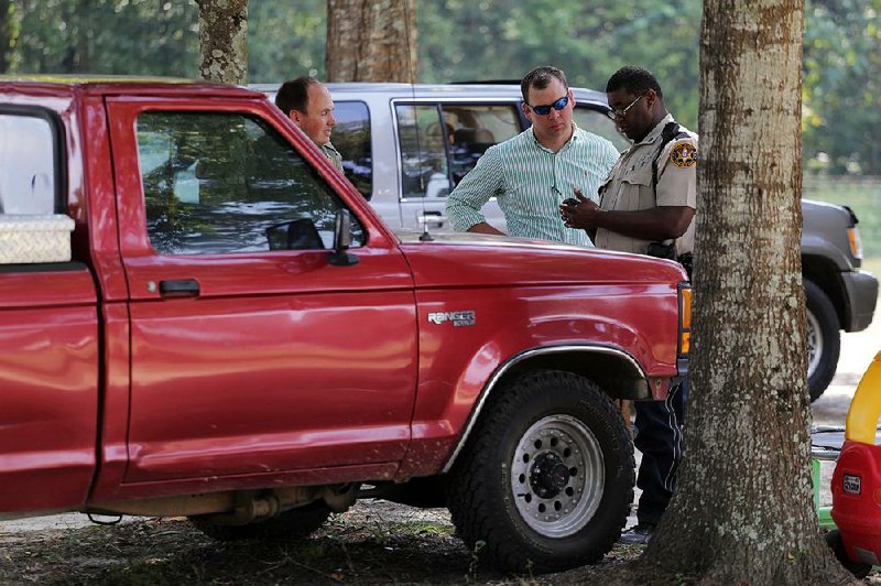 Law officers inspect a vehicle matching the description of the one used in a shooting outside Camp Shelby in Hattiesburg, Miss., on Tuesday.