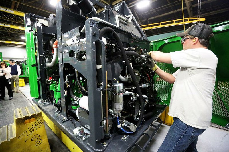 A John Deere employee works on a harvester at John Deere Dubuque Works in Dubuque, Iowa, in February. Orders to U.S. factories rose 1.8 percent in June, the Commerce Department said Tuesday. 
