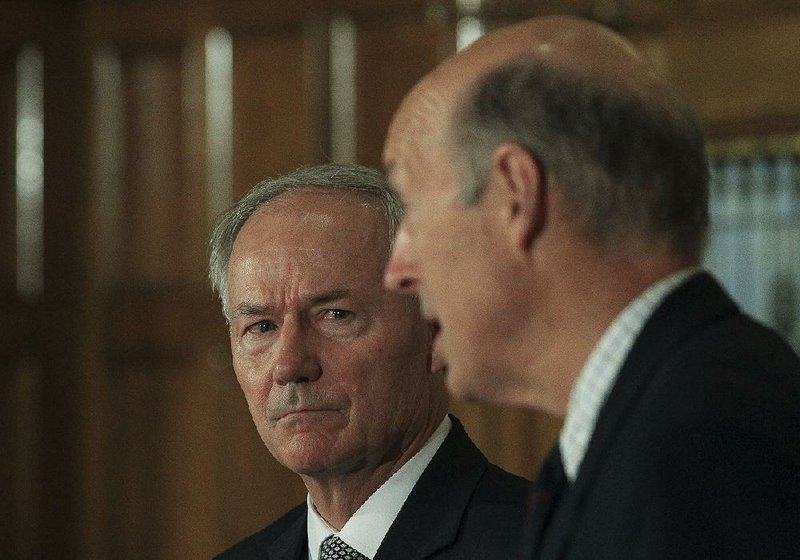 Gov. Asa Hutchinson (left), with John Selig, director of the state Department of Human Services, said Tuesday that despite the moratorium on cancellation notices, recipients would not get extra time to respond.