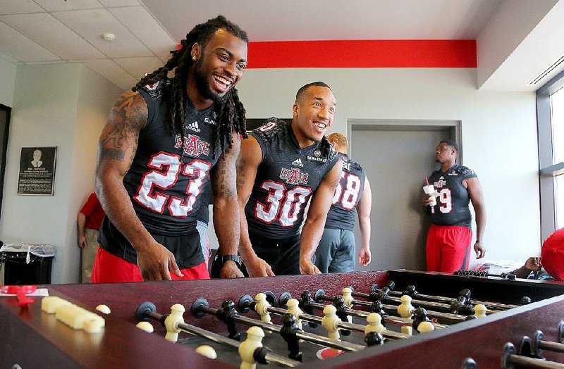 Arkansas State wide receiver J.D. McKissic (23) and running back Johnston White team together during a game of foosball as they await their turn for interviews during the Red Wolves’ media day Wednesday in Jonesboro. McKissic said he is healthy for the first time since the opening practice last fall. 