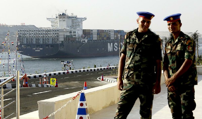 Egyptian army soldiers watch a cargo container ship cross the new section of the Suez Canal after the opening ceremony in Ismailia, Egypt, Thursday, Aug. 6, 2015. The $8.5 billion project was billed by President Abdel-Fattah el-Sissi as a historic achievement by the Egyptian people, but some economists and shippers have questioned the value of the project in a time when global trade is slowing.  