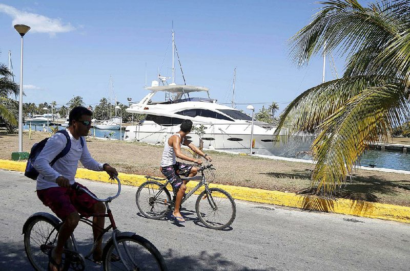 Young bicyclists pass the American yacht Still Water moored Thursday at the Hemingway Marina in Havana.  