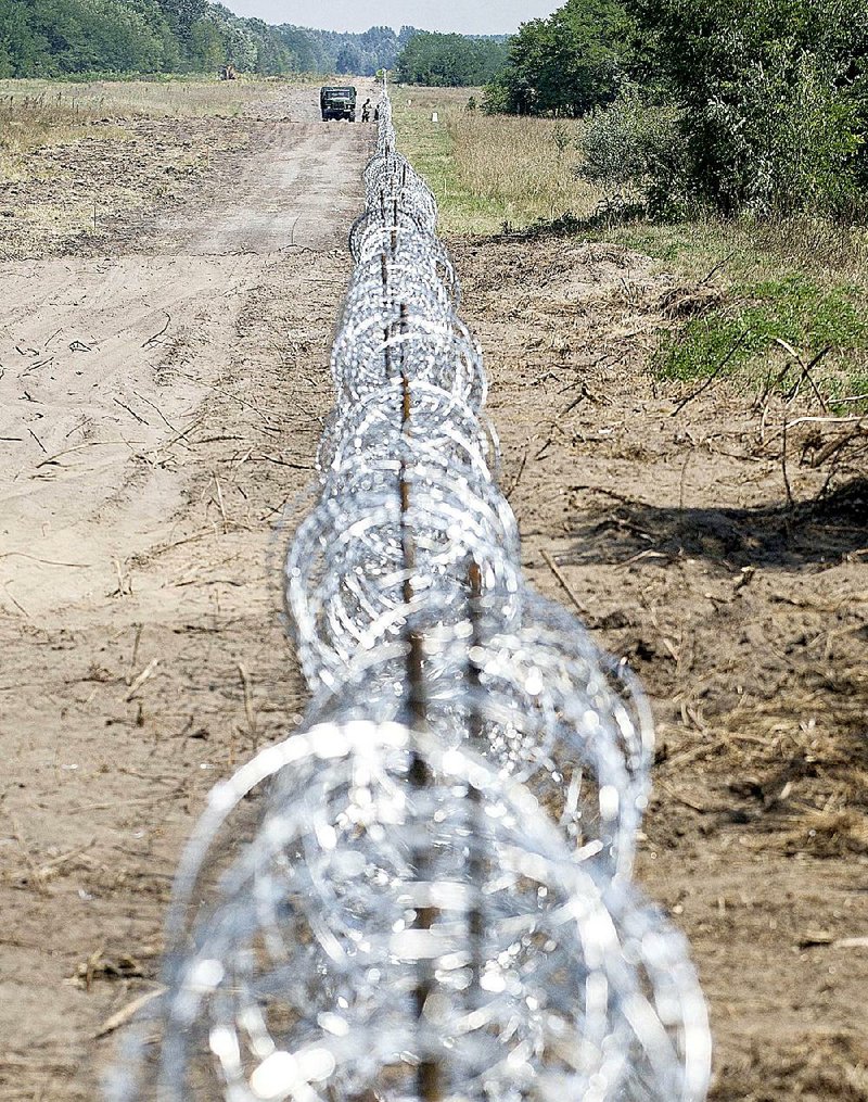 A Hungarian military truck is parked Friday next to a barbedwire section of Hungary’s southern border fence. 