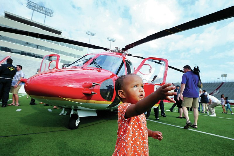 Carrie Ospring, 1, walks past one of Arkansas Children's Hospital's two new Sikorsky S-76 D helicopters Wednesday at War Memorial Stadium in Little Rock. The two aircraft are to replace earlier models in service since 2002.