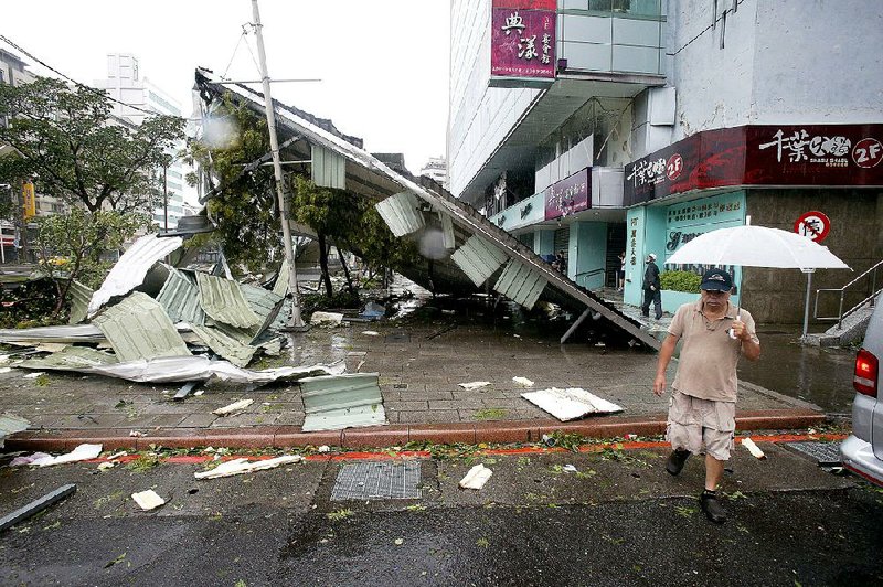 A man walking Saturday passes a structure damaged by Typhoon Soudelor in Taipei, Taiwan. 
