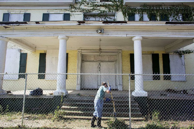 Carolyn Eastham removes debris from the front of the William E. Woodruff House in Little Rock on Saturday. Volunteers with the Quapaw Quarter Association began cleanup of the property Saturday in preparation for repair and stabilization work on the historic home. 