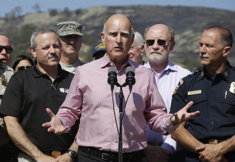 Gov. Jerry Brown, center, speaks next to Mark Ghilarducci, director of the California Governors Office of Emergency Services, left, and Cal Fire Chief Ken Pimlott, right, at a news conference at Cowboy Camp Trailhead near Clearlake, Calif., Thursday, Aug. 6, 2015. 