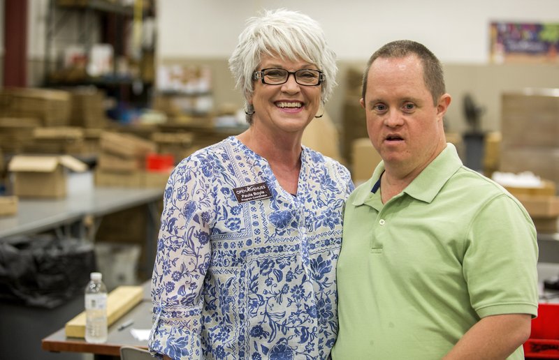 Paula Boyle, program coordinator, works with her son Jody Scoggins at Open Avenues in Rogers. Scoggins, who was born with Down syndrome, will never be able to live independently, but he goes to work each day at Open Avenues.