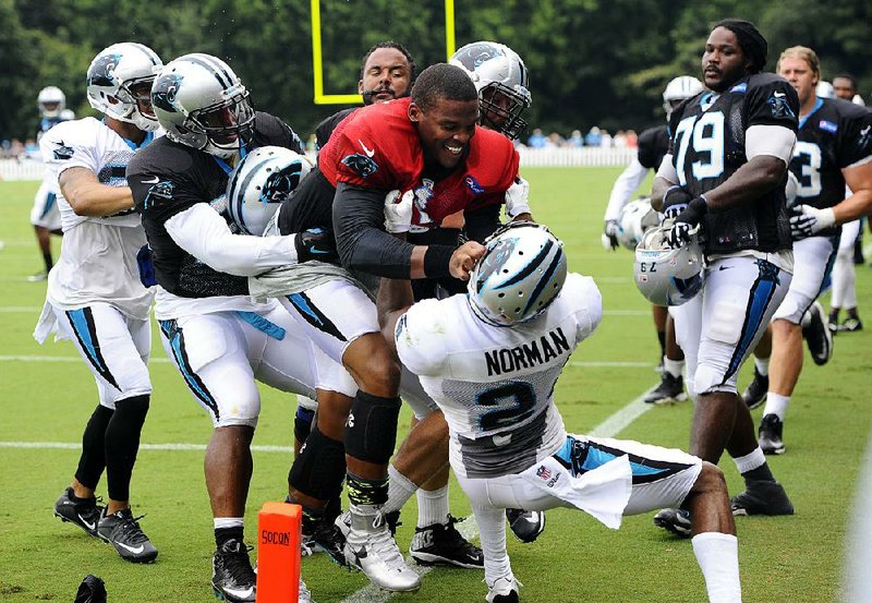 Carolina Panthers quarterback Cam Newton (center) jumps cornerback Josh Norman as teammates try to separate the two Monday at the team’s training camp in Spartanburg, S.C.