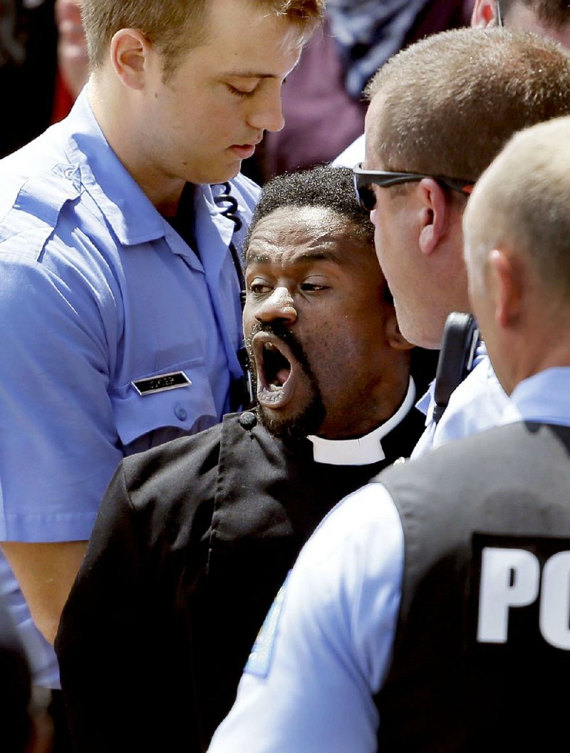 Protest organizer the Rev. Osagyefo Sekou, along with several others, is arrested by police Monday outside the Thomas F. Eagleton Federal Courthouse in St. Louis.