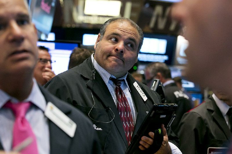 Trader Anthony Riccio (center) works on the floor of the New York Stock Exchange Tuesday, Aug. 11, 2015 Prices for oil and copper fell sharply after China's government lowered the value of its currency, suggesting weakness in the world's second-largest economy.