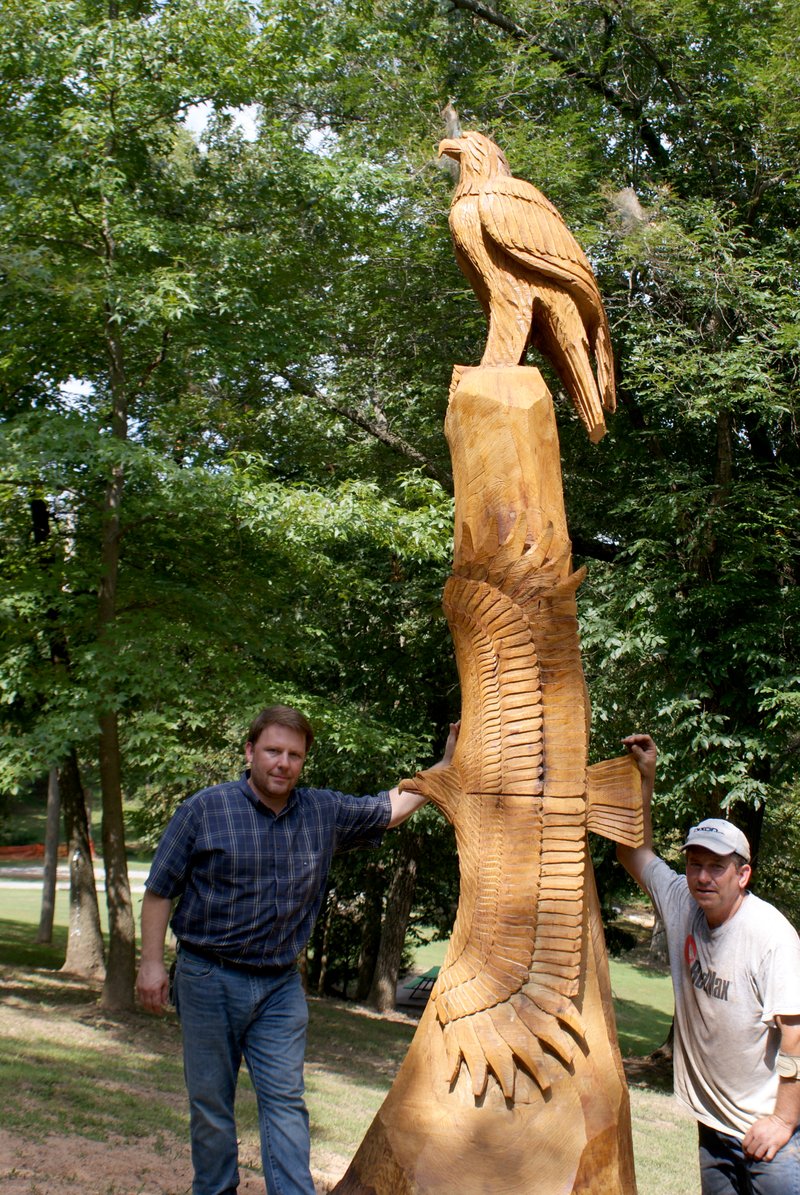 Photo by Dodie Evans Gravette mayor Kurt Maddox and chainsaw sculptor Scott Winford pose beside the bald eagle sculpture Winford created in Old Town Park.