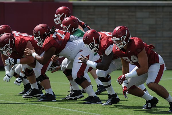 Members of the Arkansas offensive line Mitch Smothers (from left), Sebastian Tretola, and Denver Kirkland block Tuesday, Aug. 11, 2015, with tight end Hunter Henry (right) during practice at the university's practice field in Fayetteville.