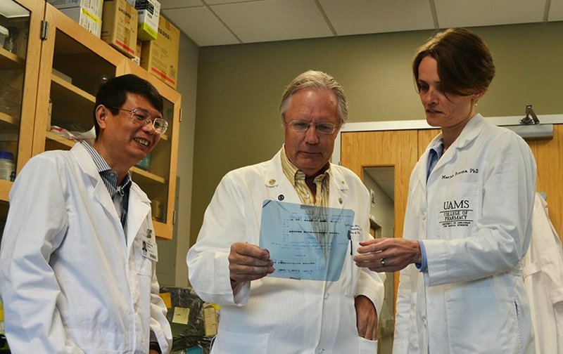 Dr. Martin Hauer-Jensen, director of the UAMS Center for Studies of Host Response to Cancer Therapy, center, looks at lab data on a transparency along with Dr.s Daohong Zhou, left, and Marjan Boerma, right.
