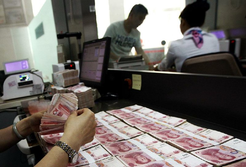 A clerk counts Chinese currency notes Tuesday at a bank in Huaibei, China. 