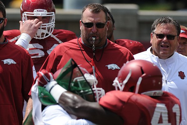 Arkansas coach Bret Bielema (left) and offensive line coach Sam Pittman watch Thursday, Aug. 13, 2015, as defensive and offensive players spar during practice at the university practice field in Fayetteville.