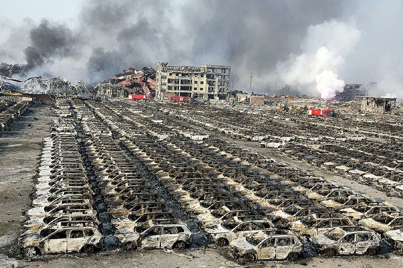 Smoke billows Thursday from the site of an explosion that reduced a parking lot filled with new cars to charred remains at a warehouse in northeastern China’s Tianjin municipality. 