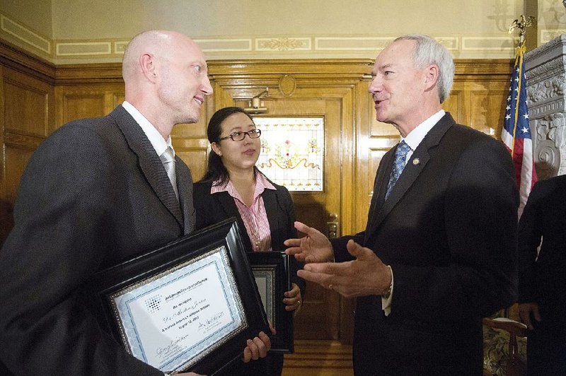 Gov. Asa Hutchinson (right) talks with Morten Olgaard Jensen and Jie Xiao on Thursday after they were named as the newest Arkansas Research Alliance scholars during a ceremony at the state Capitol.