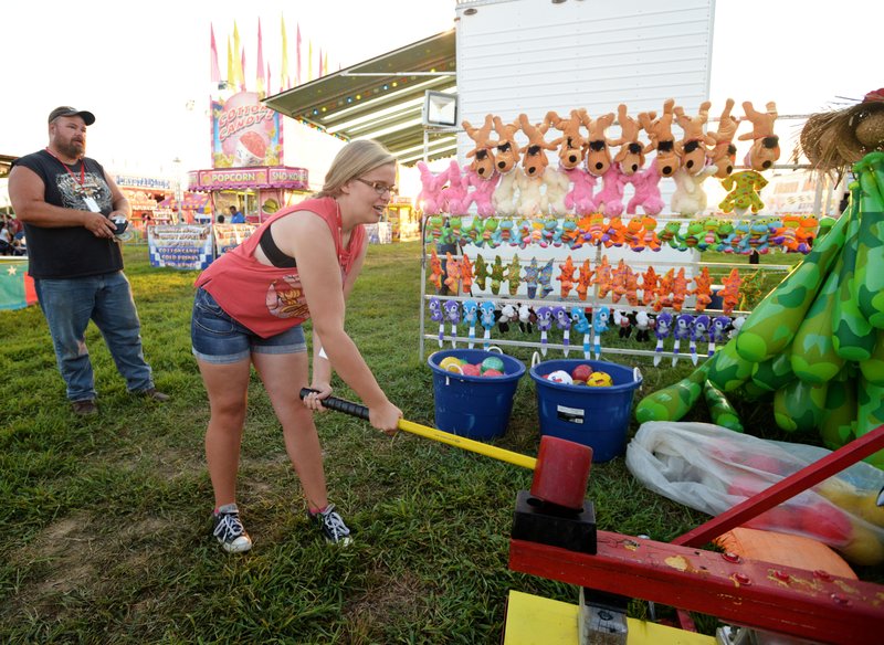 Paige Wood, 14, of Gentry, with father Robert Wood looking on, tests her strength on a game on the midway Thursday during the Benton County Fair at the Benton County Fairgrounds & Expo Center in Bentonville. For more photos, go to www.nwadg.com/photos.