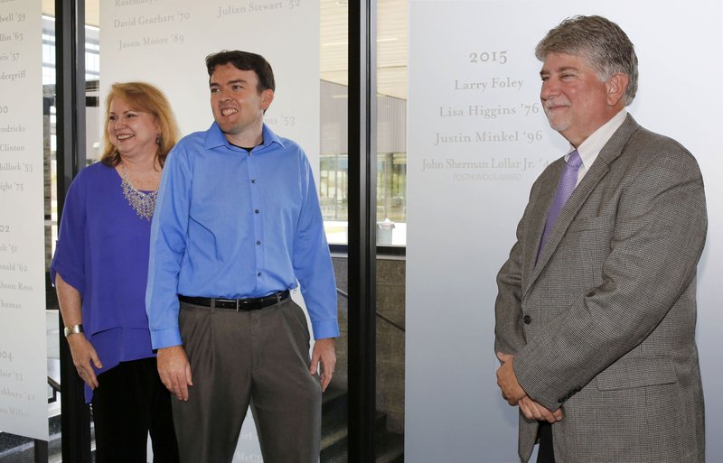 Lisa Higgins (from left), Justin Minkel and Larry Foley stand Thursday in front of their etched names on the new Hall of Honor Wall at Fayetteville High School. The newest additions to the Fayetteville Schools Hall of Honor were announced by the Fayetteville Public Education Foundation. Higgins, Minkel, and Foley were inducted along with the late John Sherman Lollar. 