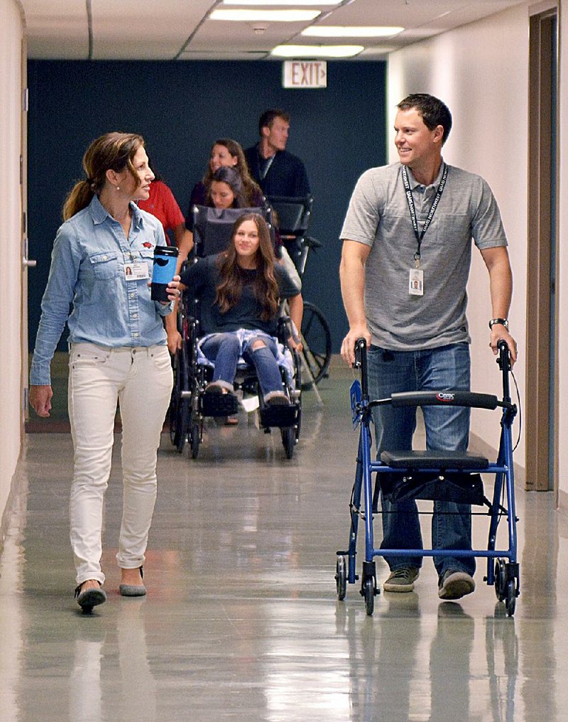 At a Friday orientation, Dr. Jennifer Vincenzo (left) talks with student Scott Van Camp as he and other new students tour the University of Arkansas for Medical Sciences building in Fayetteville in the same ways their disabled patients might. 