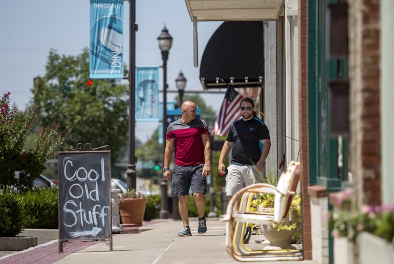 Jarrod Benningfield (left) of Springdale and Steven McDaniel of Fayetteville walk Friday along the sidewalk past businesses on Walnut Street in downtown Rogers. For photo galleries, go to nwadg.com/photos.