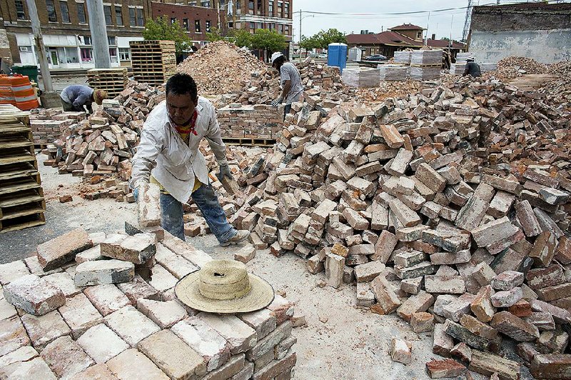 Fransisco Ramos and other workers organize bricks at a demolished building site on Aug. 6 in Pine Bluff off Main Street.