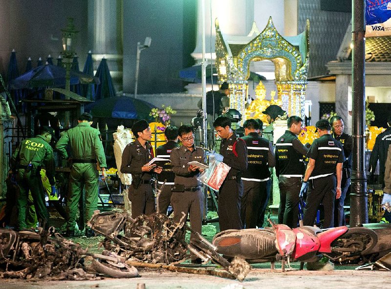 Police investigate the scene at the Erawan Shrine after an explosion there Monday in Bangkok. The bombing happened during the evening rush hour, killing 18 and injuring more than 100, police said.