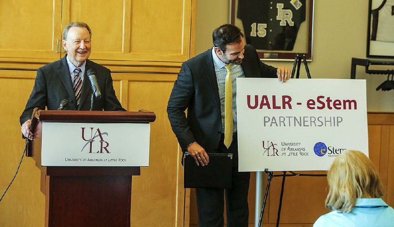 University of Arkansas at Little Rock Chancellor Joel Anderson (left) observes the audience as John Bacon, chief executive officer for eSTEM Public Charter Schools Inc., flips over a sign announcing a new partnership between the two schools Monday afternoon.