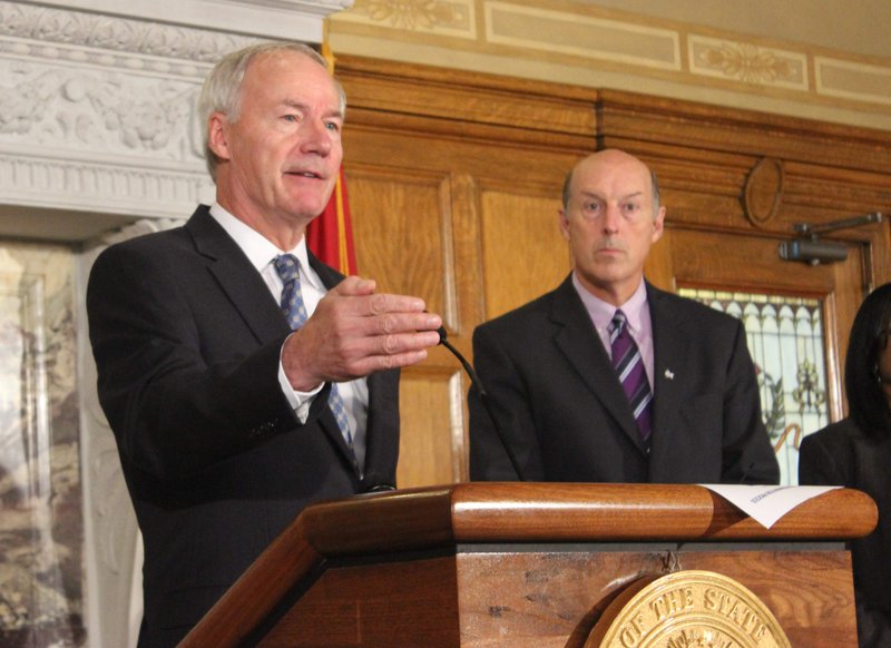 Gov. Asa Hutchinson speaks Tuesday, Aug. 18, 2015, while Department of Human Services Director John Selig looks on at a news conference at the state Capitol.