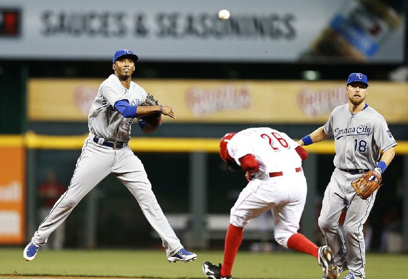 Kansas City shortstop Alcides Escobar (left) completes a double play in front of teammate Ben Zobrist and Cincinnati’s Raisel Iglesias (26) during the Royals’ 3-1 victory over the Reds in 13 innings Tuesday in Cincinnati.