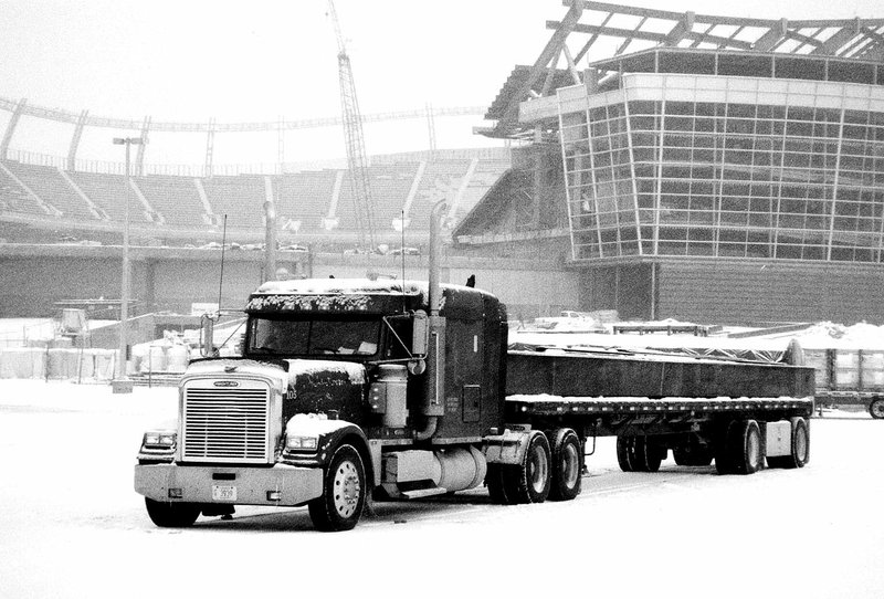 Photo by Randy Moll &#8220;Elsie Mae,&#8221; a conventional Freightliner pulling a flat-bed trailer with an over-sized steel riser, was parked in the snow before being unloaded at the Denver Bronco Stadium during the winter of 2000-2001.