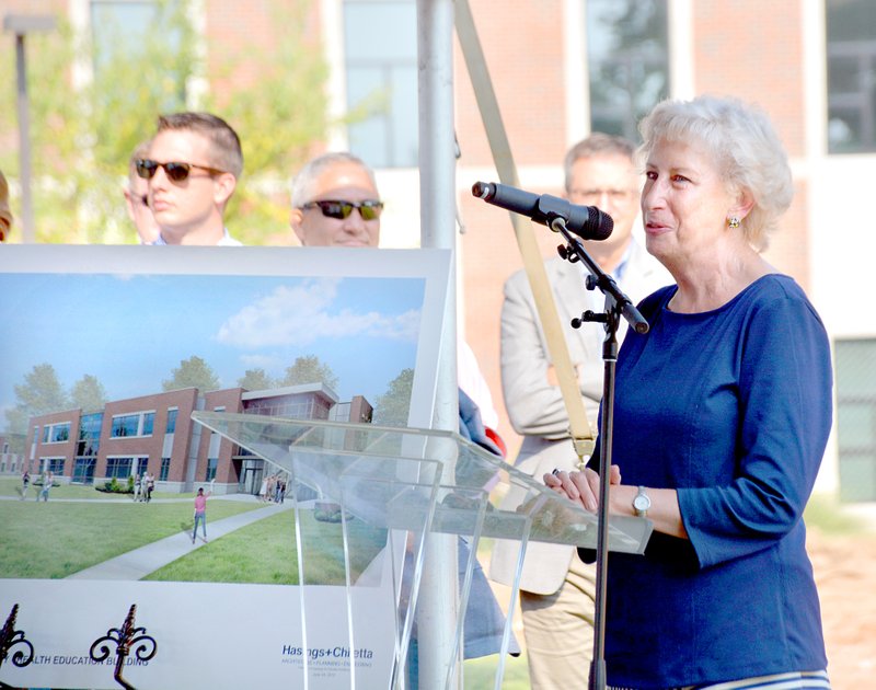 Janelle Jessen/Herald-Leader Susan Barrett, vice-president of the John Brown University board and former chief executive officer of Mercy Healthcare Systems, spoke during the groundbreaking ceremony on Monday. An architectural drawing of the new facility is in the background.