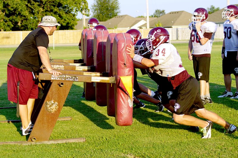 Gentry coach Justin Ledbetter worked with linemen on the sleds Thursday during practice at Gentry High School. The team will participate in a “Meet the Pioneers” event on Friday at 6 p.m. and in a varsity scrimmage at 7 p.m. on Aug. 28. The first game is set for Sept. 4 against West Fork in Pioneer Stadium.