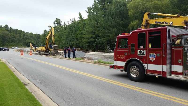 Little Rock firefighters inspect the site where a construction worker was injured Friday, Aug, 21, 2015, after dirt and rocks caved in on him in a hole along Rahling Road.