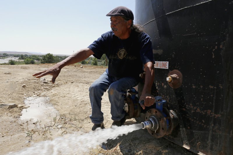 In this Aug. 18, 2015 photo, Joe Ben Jr., Shiprock Chapter House Farm Board representative, tests the water from tanks at the Chief Hill location in Shiprock, N.M.