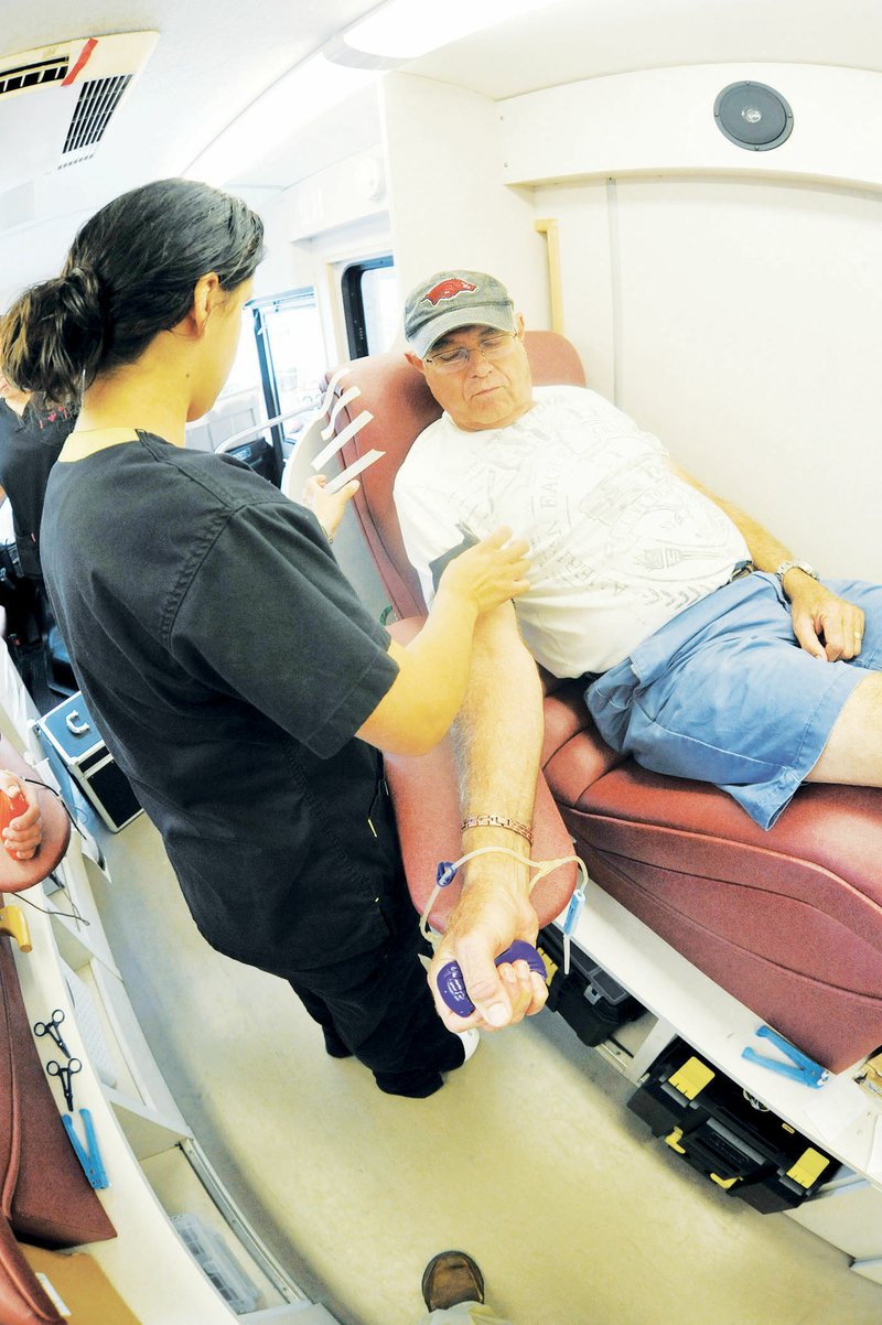 Jerry Garrett, right, prepares to give blood at a mobile unit of the Arkansas Blood Institute during a 2014 blood drive in the Walmart Supercenter parking lot in Malvern. At left is phlebotomist Vanessa Perez. Red Cross Ozarks-Arkansas Region officials have scheduled several blood drives in the Tri-Lakes Edition coverage area in the coming weeks.