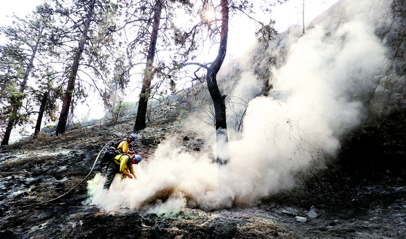 University of Alaska Fairbanks fi refi ghting students Preston Roberts (back) and Ben Schrage douse a hot spot from a wildfire Sunday in Chelan, Wash.