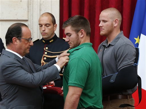 French President Francois Hollande, left, awards with the Legion of Honor Alek Skarlatos, a National Guardsman from Roseburg, Ore., while U.S. Airman Spencer Stone, right, looks on at the Elysee Palace, on Monday Aug. 24, 2015, in Paris, France.
