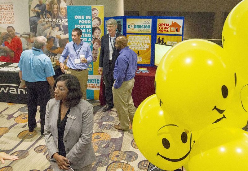 Participants in the Restore Hope Summit stand near a booth promoting foster care Tuesday at the Marriott Downtown in Little Rock. Gov. Asa Hutchinson urged attendees to help the state provide better services for foster children and for inmates who are re-entering society.