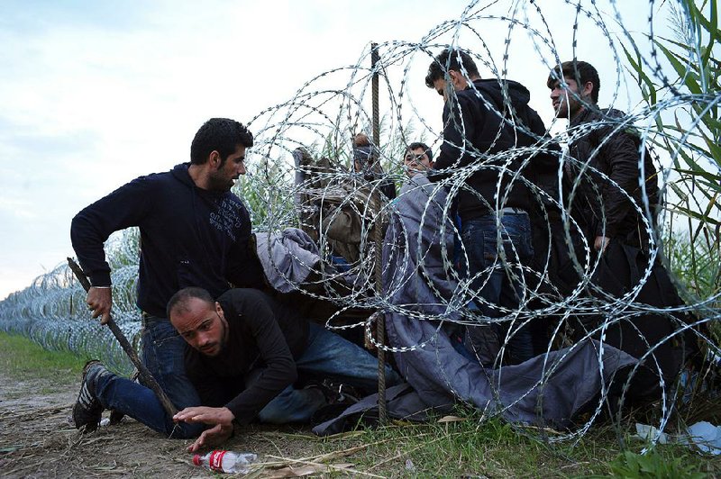 Syrian migrants scuttle into Hungary underneath a fence Wednesday at the Serbian border near Roszke, Hungary.