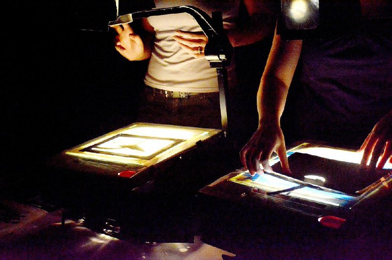 Actor/puppeteers Rivka Kuperman and Paige Carpenter prepare projections — upside down and in reverse — for The Ugly Duckling at the Arkansas Arts Center Children’s Theatre.