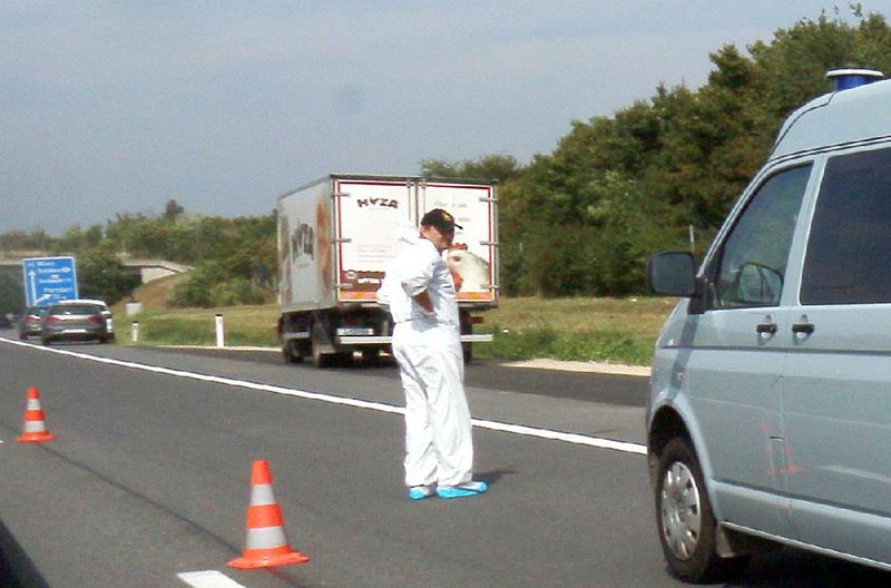 A police officer in protective gear works Thursday behind a refrigeration truck that authorities say contained migrants’ bodies and had been driven from Hungary into Austria.