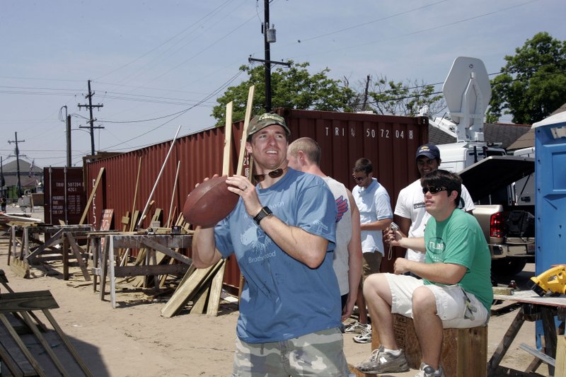 New Orleans Saints quarterback Drew Brees throws a football on May 10, 2007, to some of the workers who took a break while working on a Habitat for Humanity home in the Musicians Village in the Ninth Ward of New Orleans.