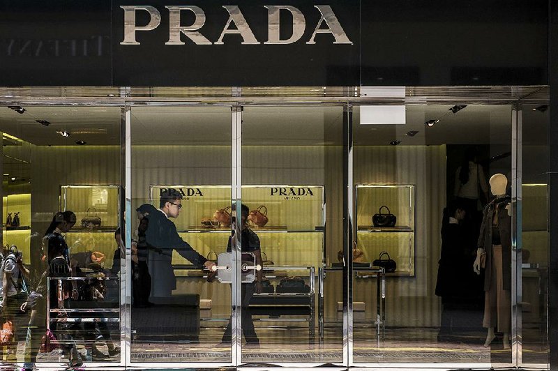 An employee stands at the door of a Prada SpA luxury fashion store on Russell Street in the Causeway Bay shopping district of Hong Kong on Aug. 8.